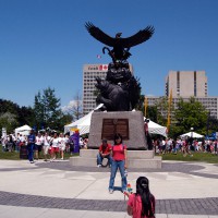 Girl posing in front of the Aboriginal Veterans Monument in Confederation Park during Canada Day celebration